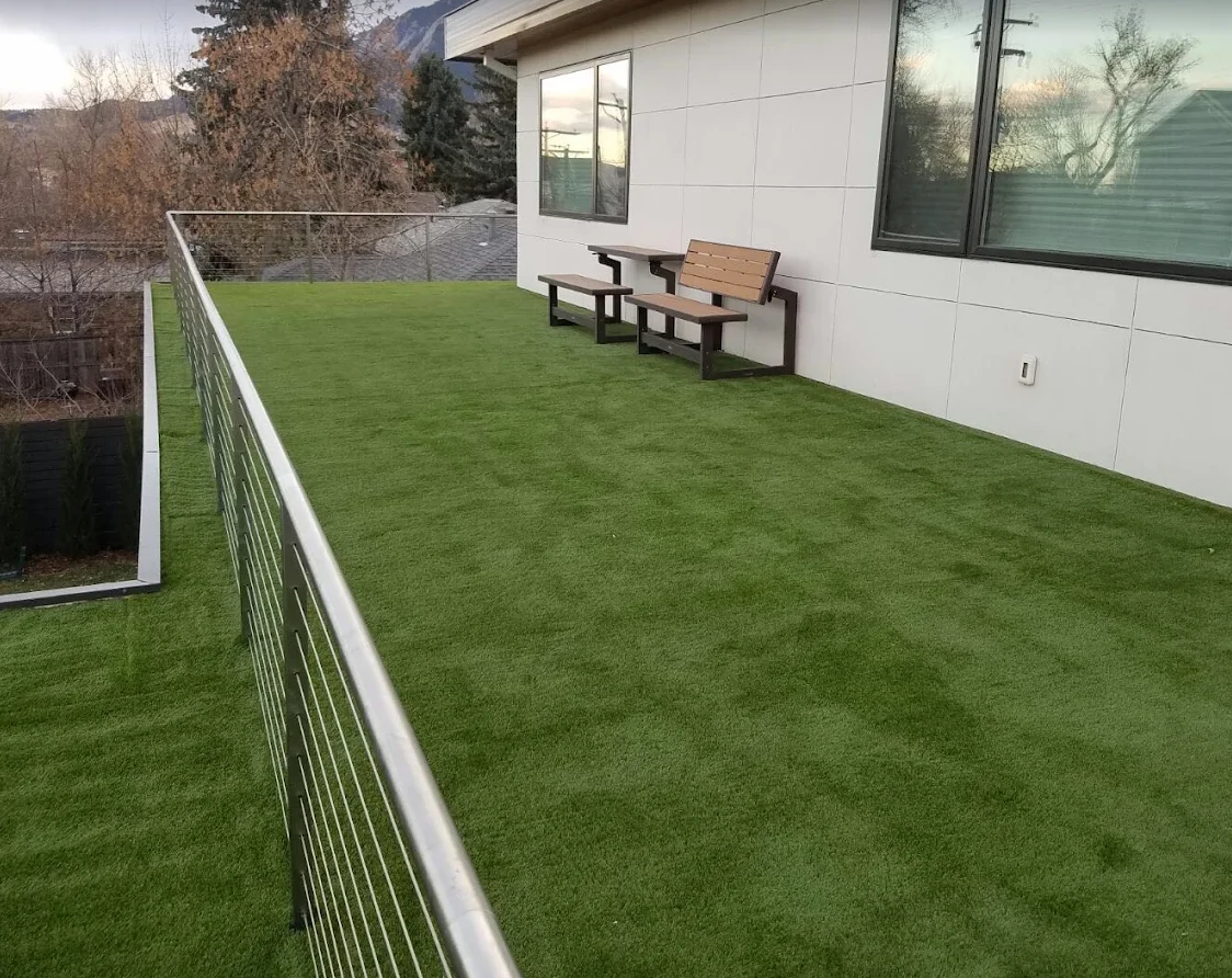 Artificial turf covering a rooftop terrace with cable railing and benches